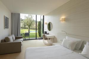 ポンテ・ダ・バルカにあるTempus Hotel & Spaのベッド、デスク、ソファが備わるホテルルームです。