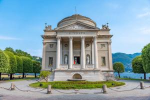 un gran edificio en un parque junto a un cuerpo de agua en Romantic White Apartment - 5 minutes from the lake, en Como