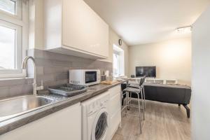 a kitchen with a sink and a dishwasher at Cosy Heathrow Apartment - Free Parking in Colnbrook