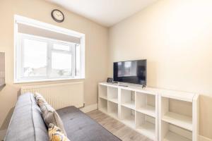 a living room with a couch and a tv and a window at Cosy Heathrow Apartment - Free Parking in Colnbrook