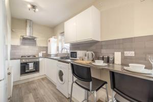 a kitchen with white cabinets and a washer and dryer at Cosy Heathrow Apartment - Free Parking in Colnbrook