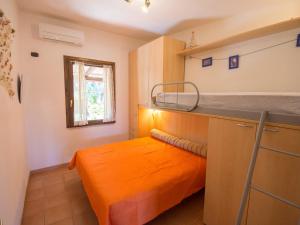 Cama naranja en habitación pequeña con ventana en Villetta Cala Petralana, en Porto Pollo