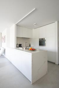 a white kitchen with white cabinets and a sink at Genieten in Groenendijk Oostduinkerke Koksijde - Vitamine Zee in Koksijde