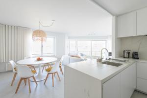 a white kitchen with a table and chairs at Genieten in Groenendijk Oostduinkerke Koksijde - Vitamine Zee in Koksijde