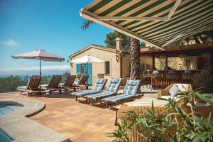 a group of lounge chairs and an umbrella on a patio at Mediterranean Sea View Villa in Port d’Andratx