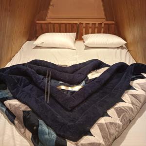 Hawk Camping & Cottages في ناينيتال: بطانية زرقاء موضوعة فوق السرير