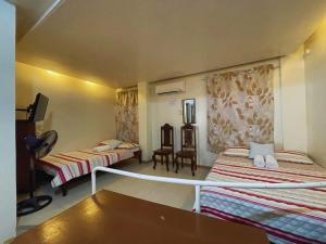 Habitación con 3 camas y mesa. en Villa Pamana Inn Puerto Galera powered by Cocotel, en Puerto Galera