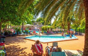 a group of people laying in lawn chairs near a swimming pool at Camping Les Pêcheurs - Maeva in Roquebrune-sur-Argens