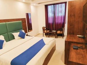 um quarto com uma cama, uma cadeira e uma janela em Hotel Tela Suite Plaza Near IGI Airport em Nova Deli