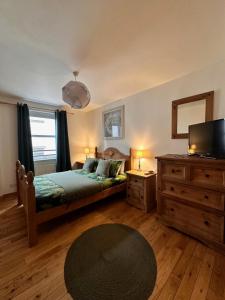 a bedroom with a bed and a television and a dresser at City centre apartment next to Bus and Train Station in Inverness +5 photos