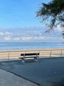 a bench sitting next to a beach with the ocean at Grande maison neuve à 100 m de la plage in Pléneuf-Val-André