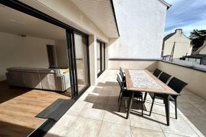 a patio with a table and chairs on a balcony at Grande maison neuve à 100 m de la plage in Pléneuf-Val-André