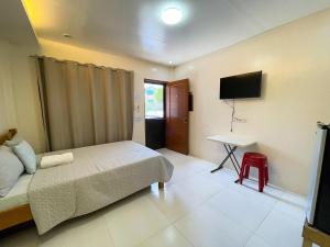 1 dormitorio con 1 cama, TV y mesa en Villa Pamana Inn Puerto Galera powered by Cocotel, en Puerto Galera