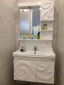 een witte badkamer met een wastafel en een spiegel bij استراحة هيلا الخير in Şulbūkh
