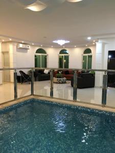 een zwembad in een kamer met een woonkamer bij استراحة هيلا الخير in Şulbūkh