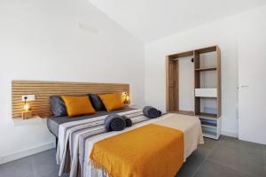 ein Schlafzimmer mit einem großen Bett mit orangefarbenen Kissen in der Unterkunft Las Cuestitas Relax in Pájara