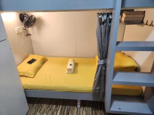 a small room with a bunk bed with a phone at Sinhassan dormitory hostel Juhu in Mumbai