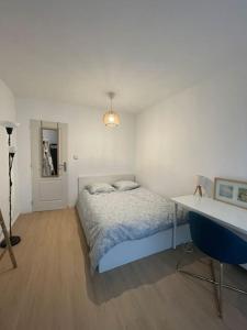 ein weißes Schlafzimmer mit einem Bett und einem Schreibtisch in der Unterkunft Bel appartement tout confort aux Portes de Paris in Cergy