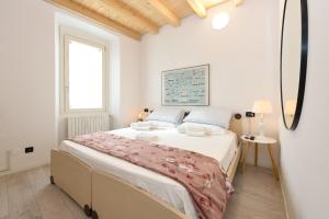 una camera bianca con un grande letto e una finestra di Casa Daniela a Desenzano del Garda