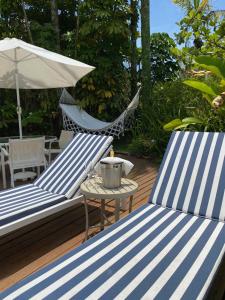 two blue and white chairs and a table and an umbrella at Guest House Guarujá Hotel Boutique in Guarujá