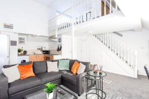 a living room with a couch and a staircase at Loft Style Apartment w/ Parking, in Leigh-on-Sea in Southend-on-Sea