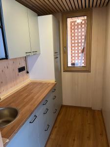 cocina con armarios blancos, fregadero y ventana en Tiny House Brunn am Gebirge en Brunn am Gebirge