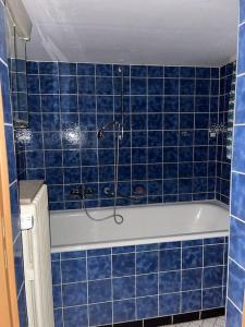 Un baño con azulejos azules y bañera con ducha. en Ferienhaus, Kassels bester Lage, en Kassel