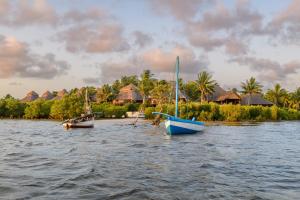 two boats in the water in front of a resort at Ocean Pearl Beach Lodge in Vilanculos