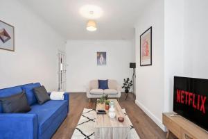 a living room with a blue couch and a tv at 4 BR House/Free Parking/5mins Walk To Kensal Rise in London