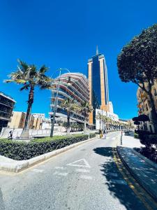 una strada cittadina con palme e un edificio alto di St Julian Luxury Apartment Wish Malta a Paceville