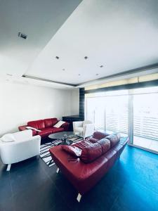 un soggiorno con divano rosso e sedie bianche di St Julian Luxury Apartment Wish Malta a Paceville