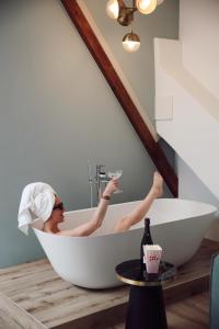 a woman sitting in a bath tub with a glass of wine at Hotel Botanique Breda in Breda