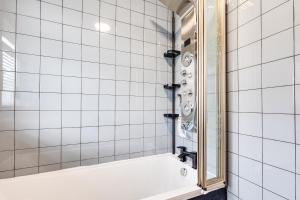 Baño de azulejos blancos con bañera y espejo en Lavish 2BR Bungalow Retreat in Birkenhead en Birkenhead