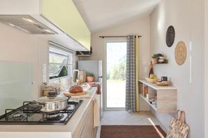 a kitchen with a stove and a refrigerator at Camping Le Canada-Insolite in Chiny