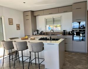 een keuken met een keukeneiland met barkrukken bij Villa Standing - Piscine et Vue Mer in Alata