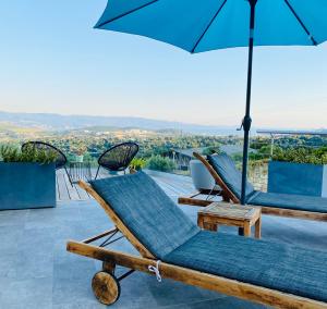 een patio met 2 ligstoelen en een parasol bij Villa Standing - Piscine et Vue Mer in Alata