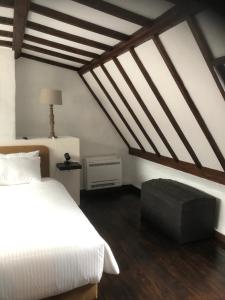 een slaapkamer met een wit bed en houten plafonds bij De Pelgrim in Tongeren