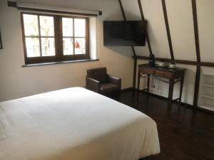 a bedroom with a bed and a chair and a television at De Pelgrim in Tongeren