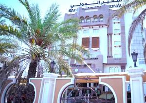 a building with palm trees in front of a building at Saḟeer international alkhuwair in Muscat