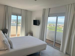 ein Schlafzimmer mit einem weißen Bett und einem großen Fenster in der Unterkunft Hotel Aromar in Platja  d'Aro