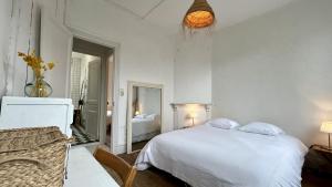 Un dormitorio blanco con una cama y un espejo. en Le Grain de Sable, en Le Crotoy