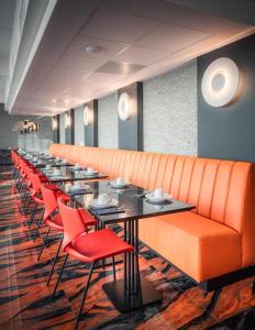 a long row of tables and red chairs in a restaurant at Hotel Jamingo in Antwerp