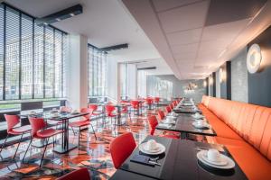 um restaurante com cadeiras vermelhas, mesas e janelas em Hotel Jamingo em Antuérpia