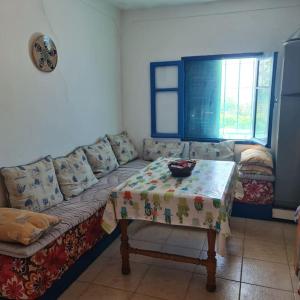ein Wohnzimmer mit einem Sofa und einem Tisch in der Unterkunft Maisonnette vue mer en pleine campagne. Originale. in El Jadida