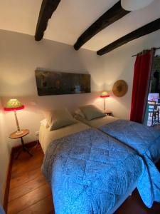 a bedroom with a blue bed with two lamps at Gîte Maison Maitri in Forgès