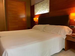 una camera da letto con un grande letto bianco con testiera in legno di Hotel Balneario Valle del Jerte a Valdastillas