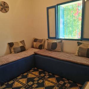 ein Sofa mit Kissen in einem Zimmer mit Fenster in der Unterkunft Maisonnette vue mer en pleine campagne. Originale. in El Jadida