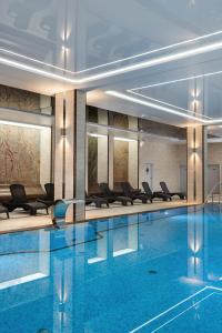 a pool in a hotel with chairs and tables at Juvena Hotel Wellness & SPA in Międzywodzie
