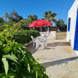 eine Terrasse mit einem Tisch und einem roten Regenschirm in der Unterkunft Maisonnette vue mer en pleine campagne. Originale. in El Jadida