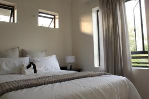 a bedroom with a large white bed with windows at Jackal Creek Golf Estate in Roodepoort